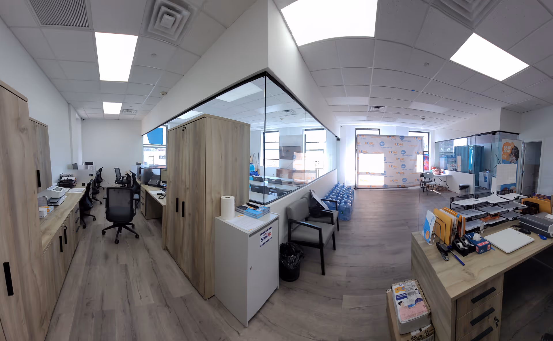 Bright office area with desks, cabinets, and glass partitions inside a senior facility.