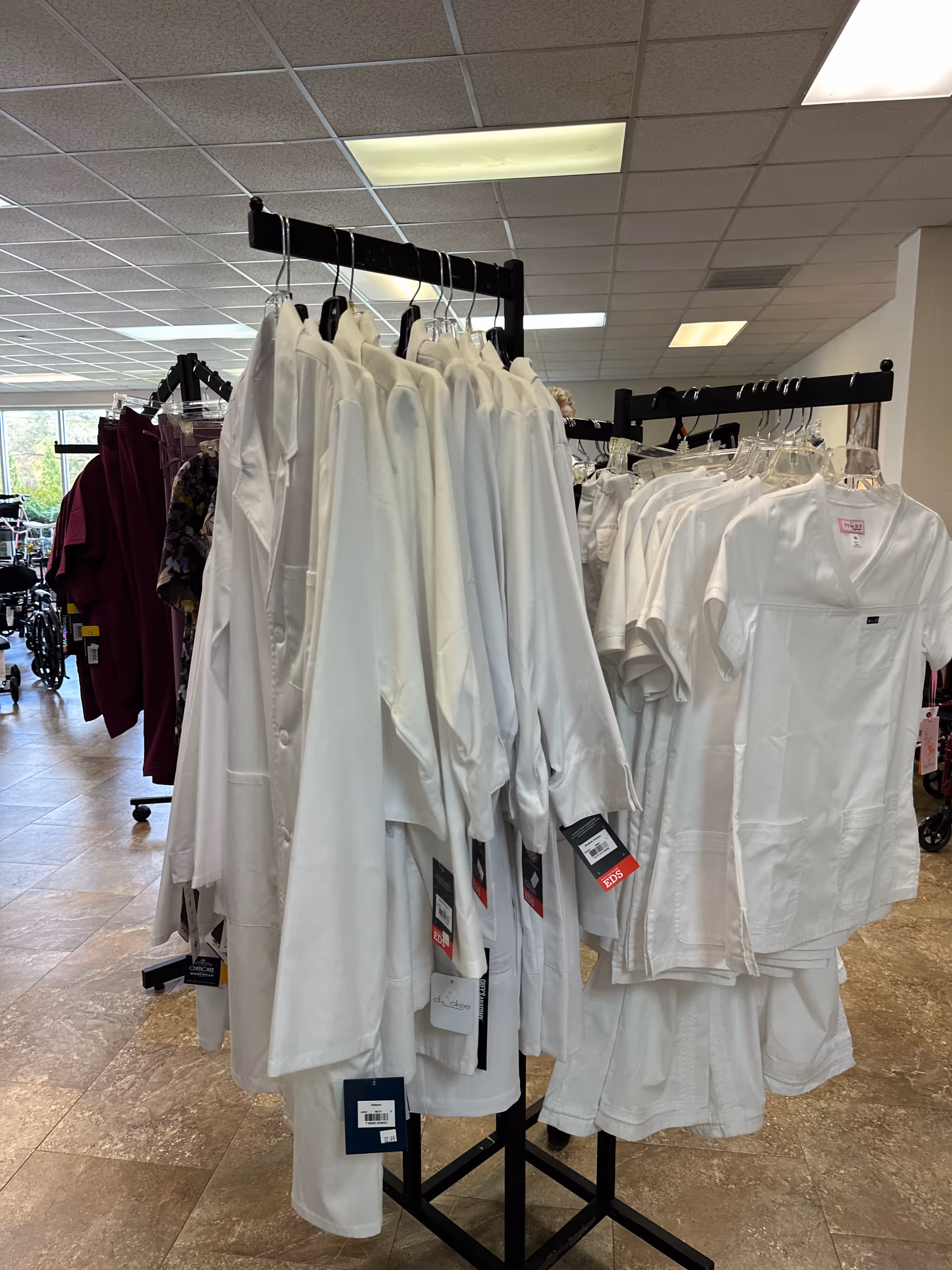 Racks of white coats on display inside an interior facility shop.