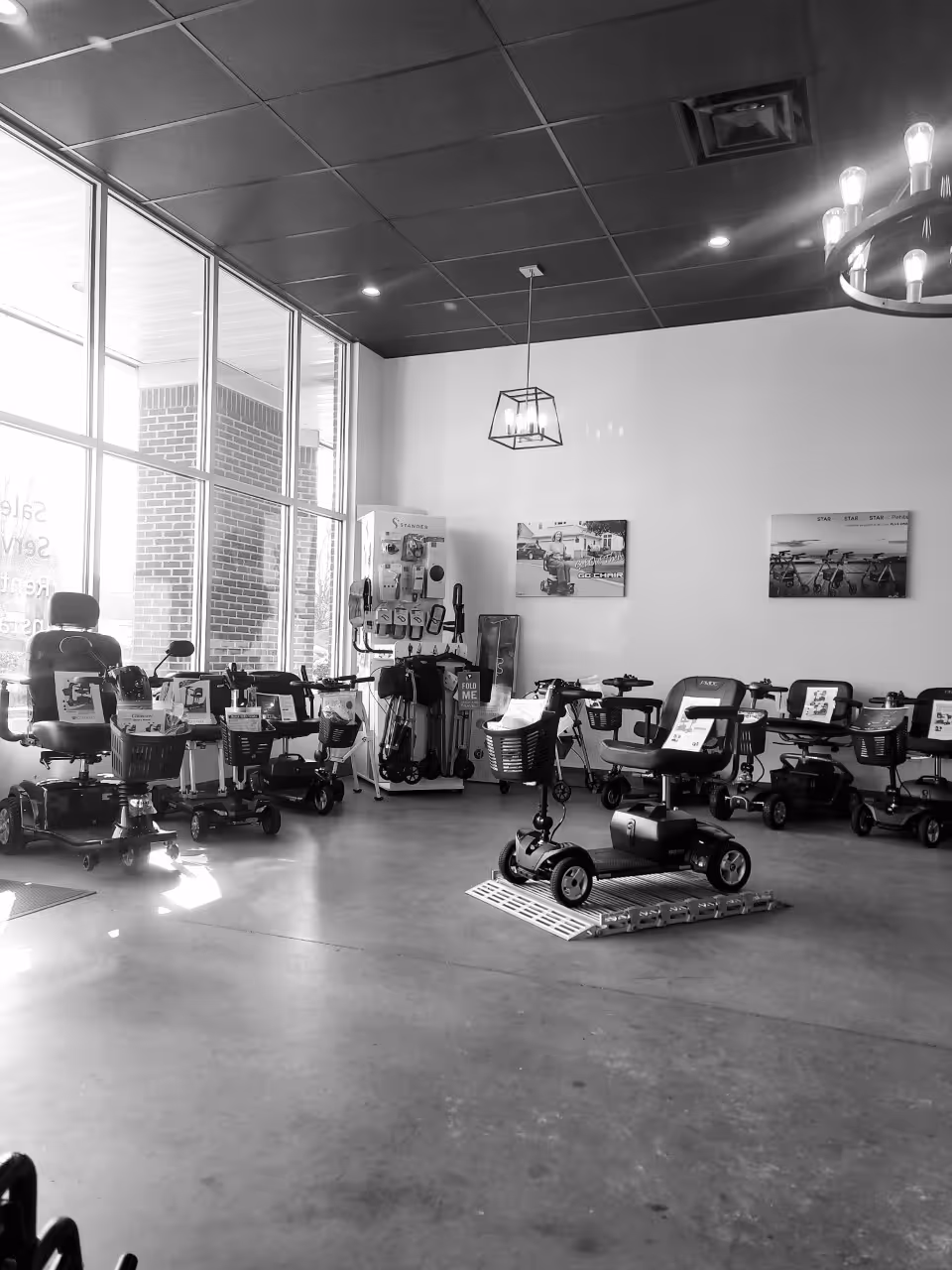 Interior showroom displaying mobility scooters and devices arranged near large windows.
