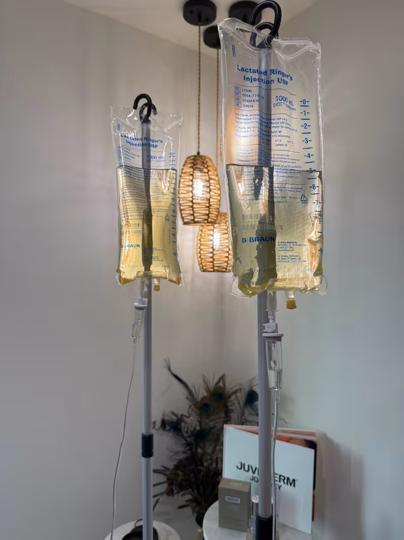 Two IV infusion bags on stands in a modern medical room with pendant lights.
