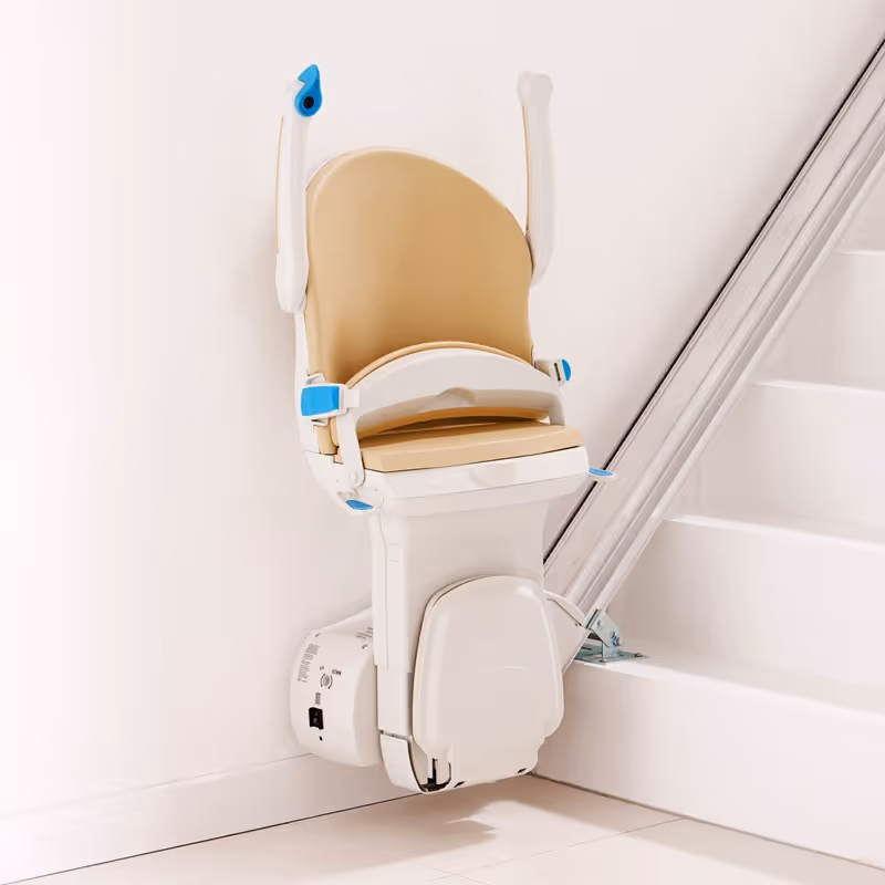 Beige stairlift chair mounted on wall beside a staircase in a clean interior.
