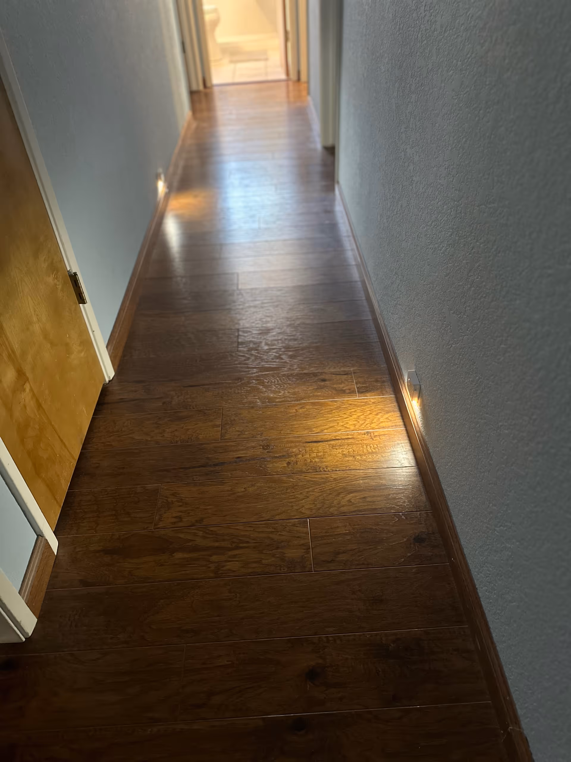 Polished wooden hallway inside a senior living facility with blue walls.