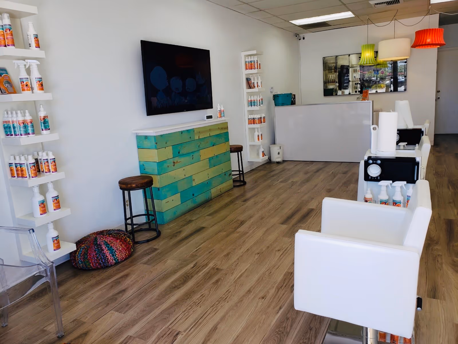 Modern salon-like treatment center interior with white chairs, bottle shelves, and a reception desk.