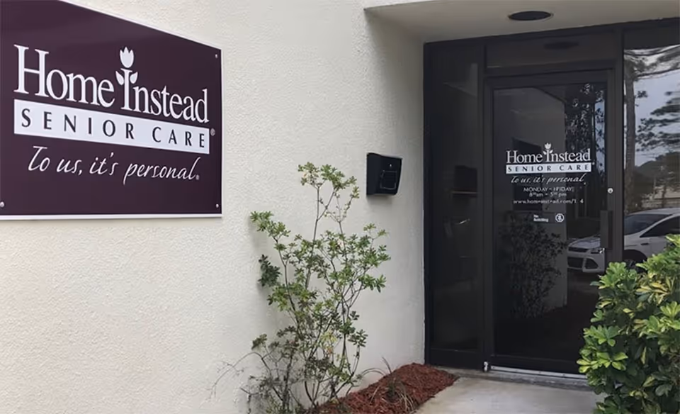 Exterior view of Home Instead Senior Care entry with sign and glass door.