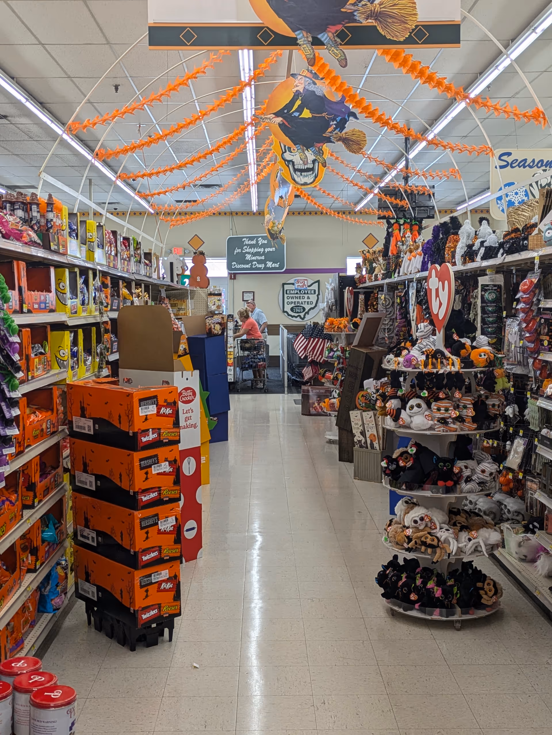 Inside Discount Drug Mart, a long aisle is lined with shelves and decor.