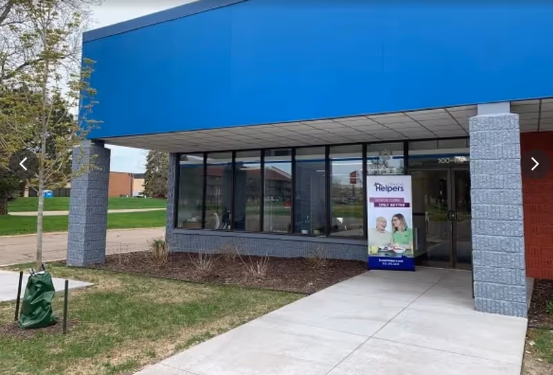 Exterior view of a Senior Helpers facility with blue awning and glass entrance.