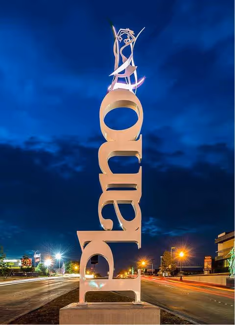 Tall metallic AccuAid sculpture sign on a city street at night.
