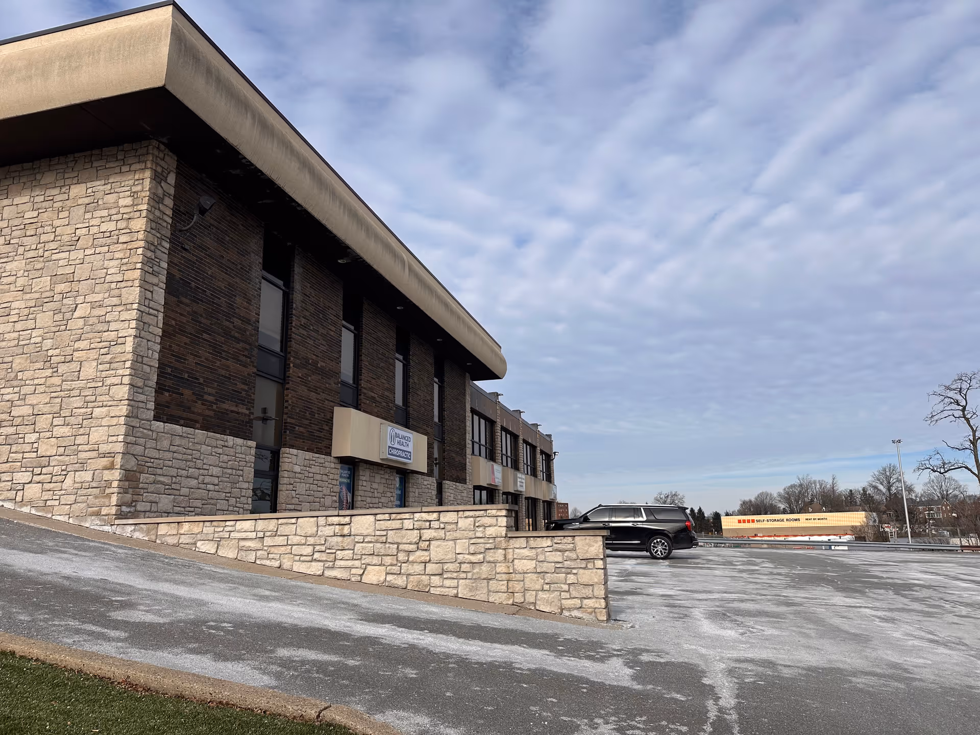 Exterior view of a stone-brick senior care facility with a parking lot.