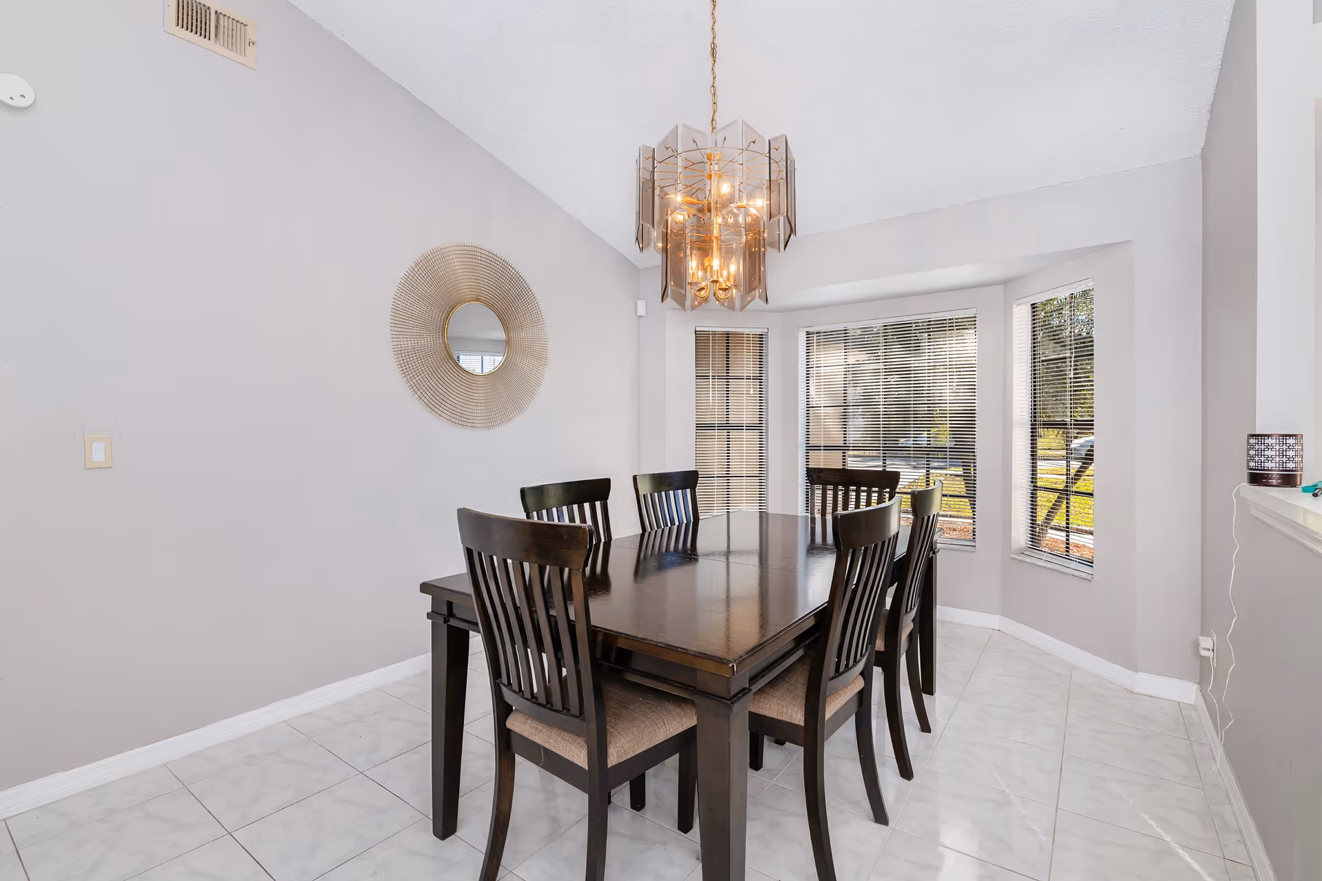 Chandelier above a dark dining table in a bright, modern dining area.