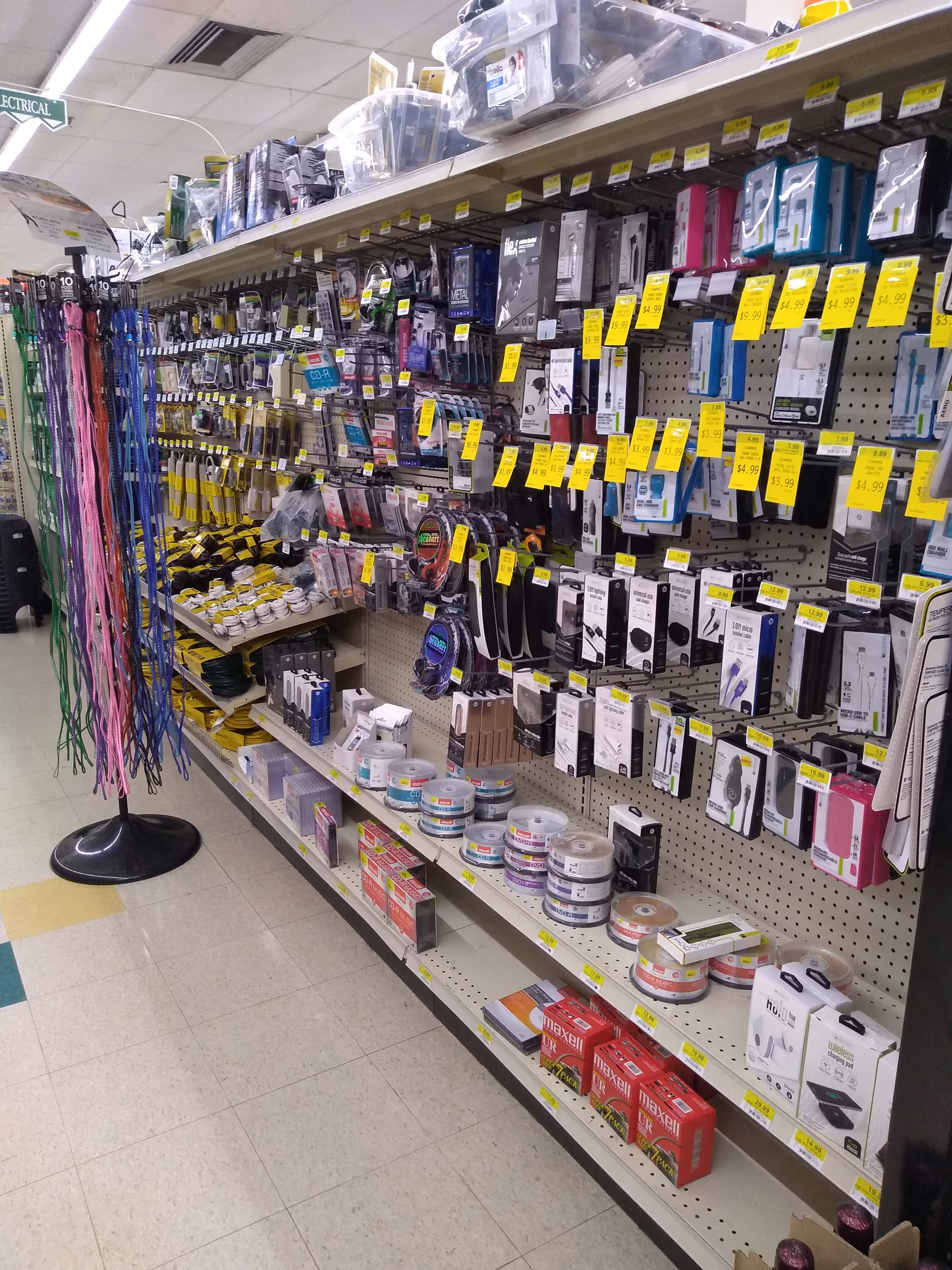 Store aisle with pegboard shelves displaying electronics accessories and cords.