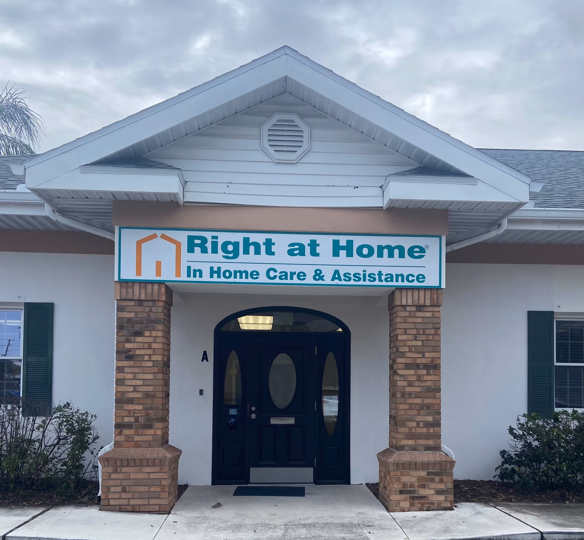 Front entrance of Right at Home facility with teal signage and brick columns.