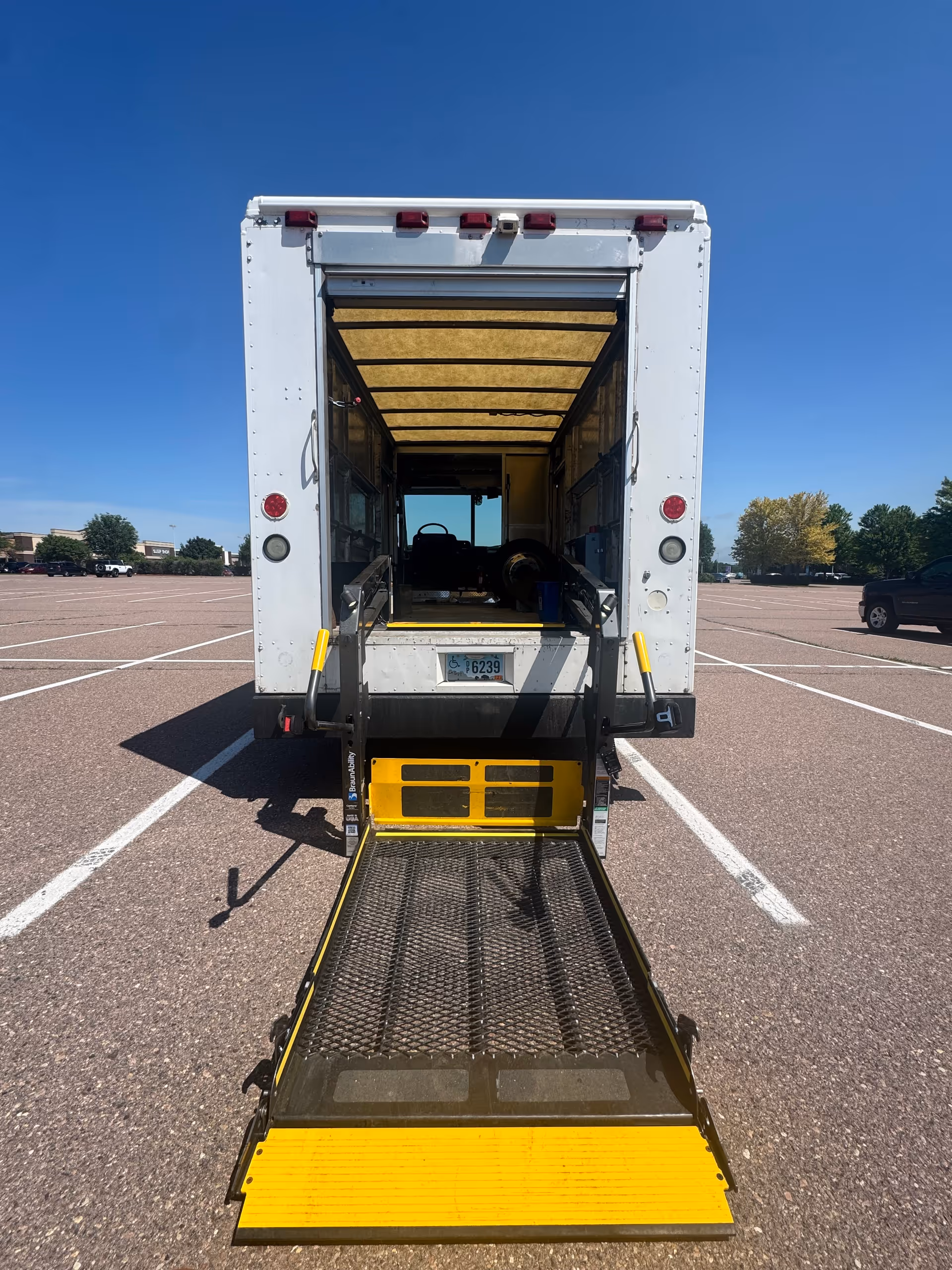 Rear view of a mobility transport van with ramp in a parking lot.
