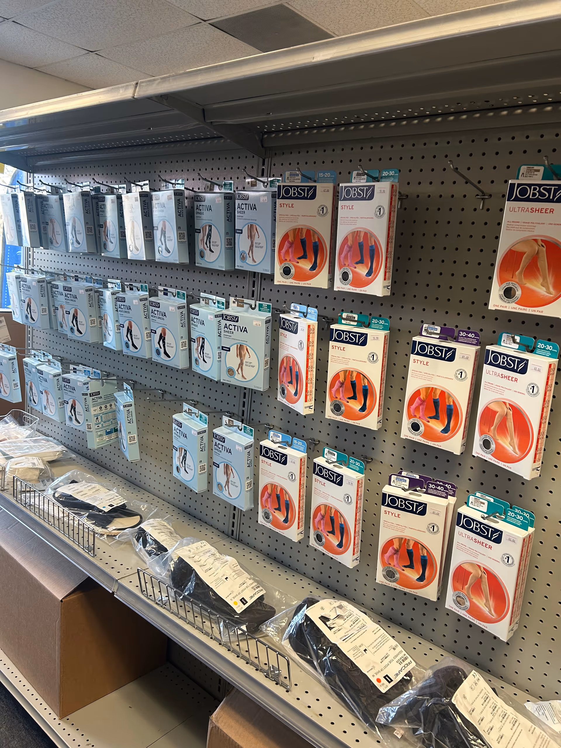 Rows of JOBST compression stockings in boxes on pegboard shelves inside a facility.