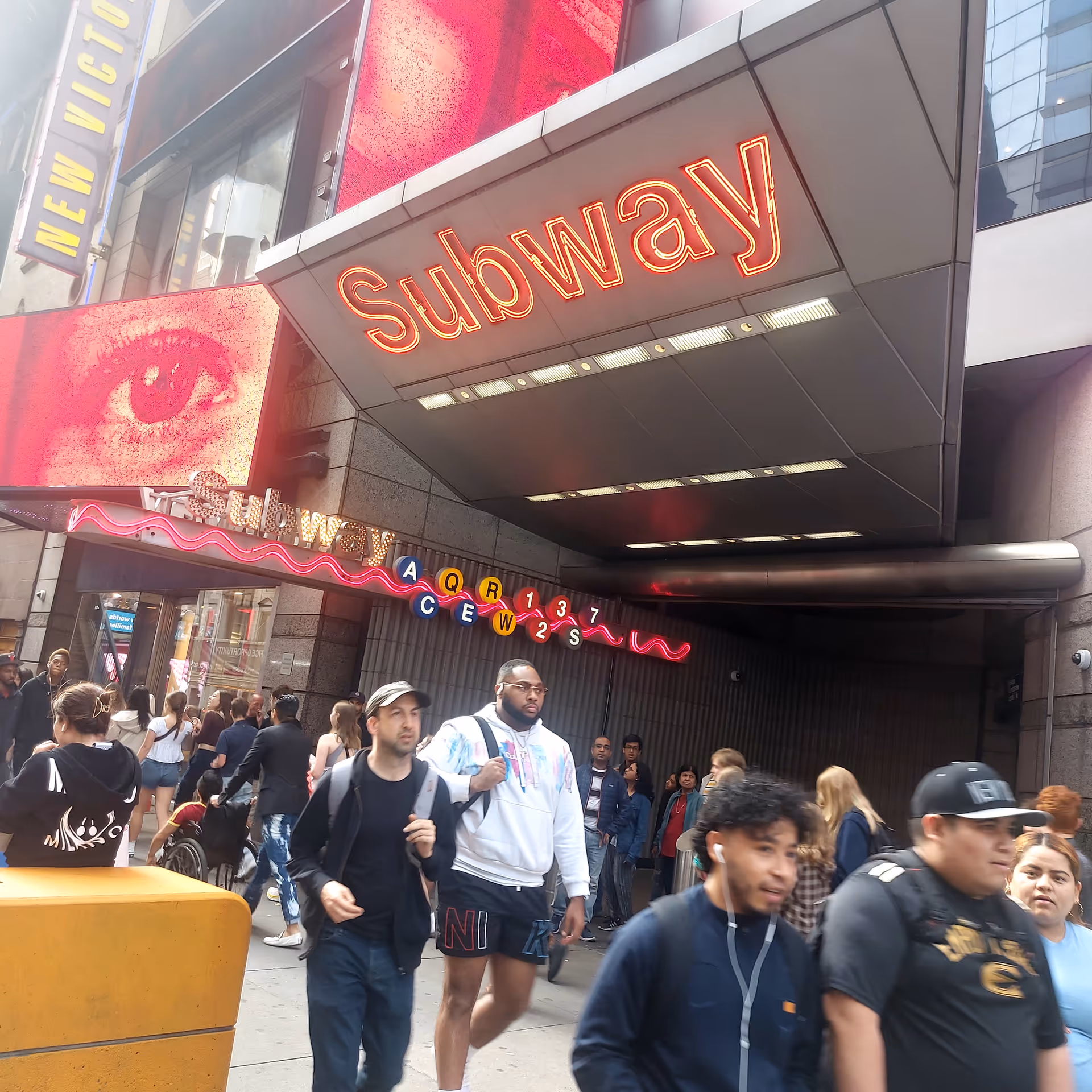 Busy urban sidewalk outside a Subway restaurant with diverse pedestrians.