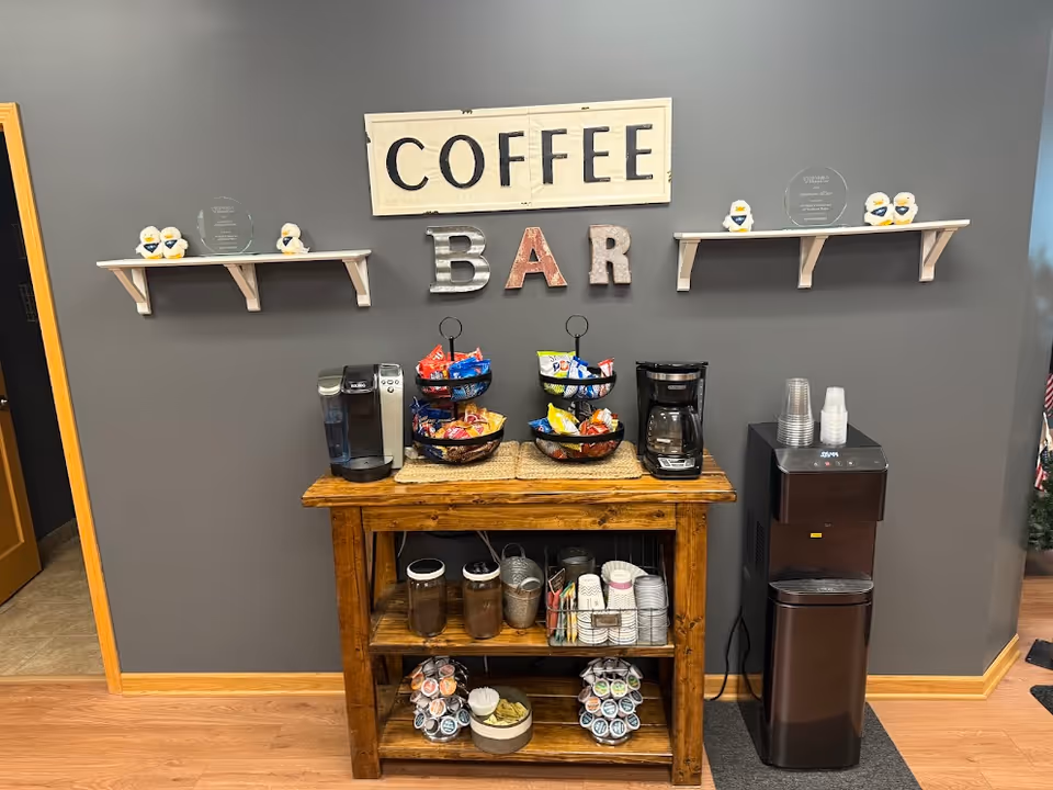 Cozy interior coffee bar with sign, snack baskets, and beverage station.