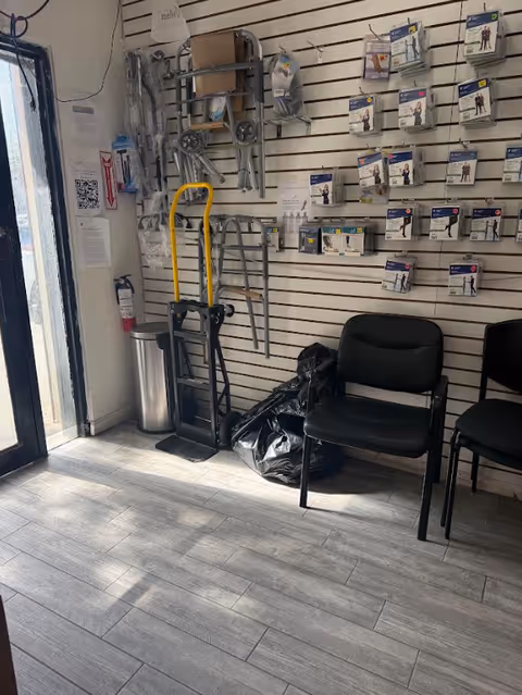 Interior supply area with wall-mounted medical accessories, chairs, a hand truck, and bags.