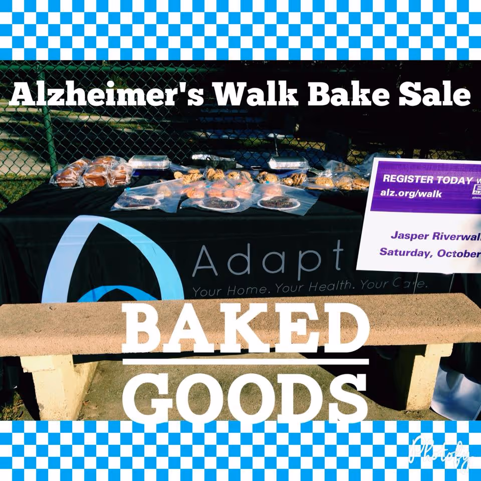 Outdoor bake sale table with desserts and Alzheimer's Walk Bake Sale banner.