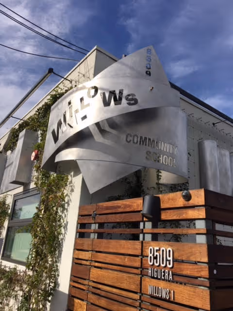Exterior view of a building with a curved metal sign reading Willows Community School.