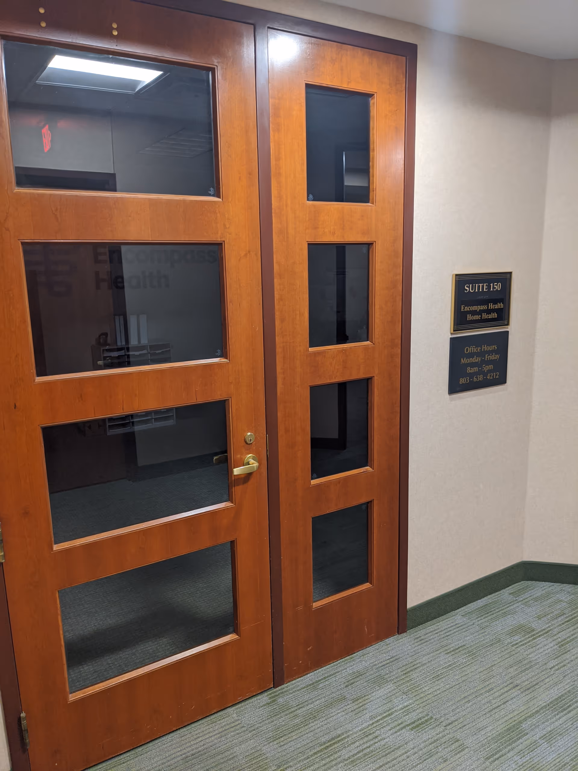 Interior hallway with tall wooden doors and a Suite 150 wall plaque