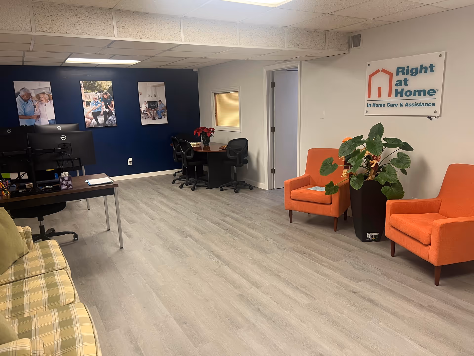 Lobby area with orange chairs, plants, and a Right at Home sign on a blue wall.