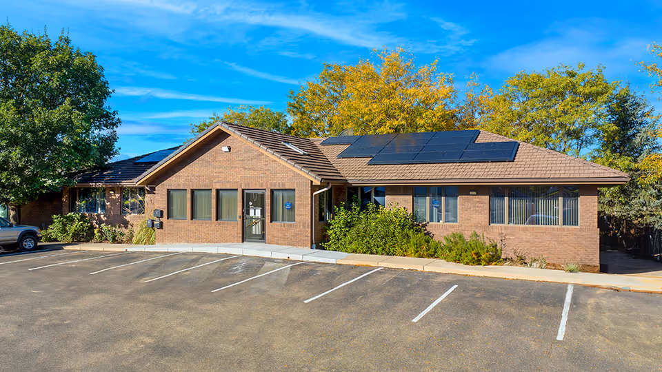 Brick Banner Hospice facility with solar panels and a parking lot under a blue sky.