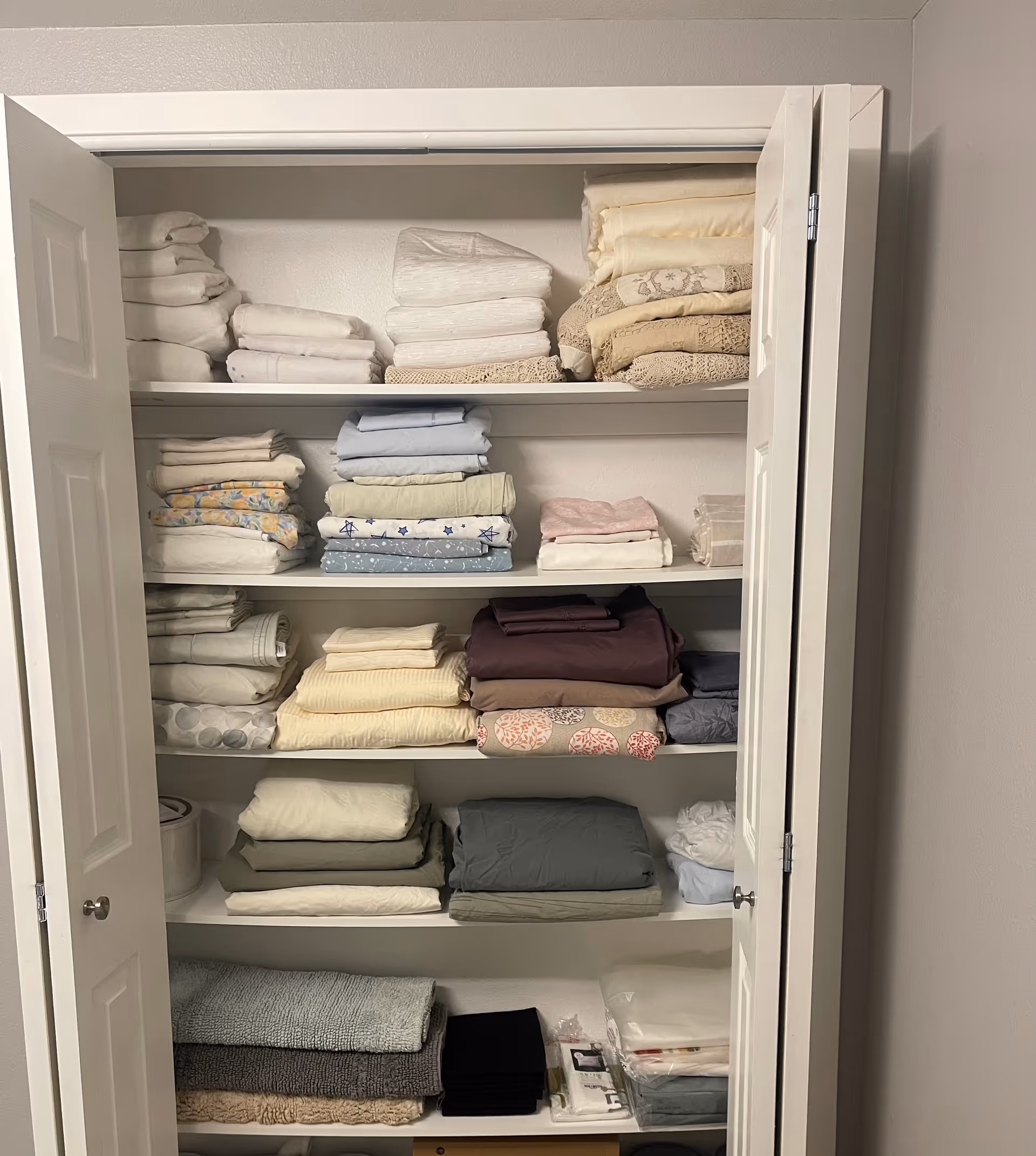 Open linen closet with neatly folded towels and sheets on shelves.