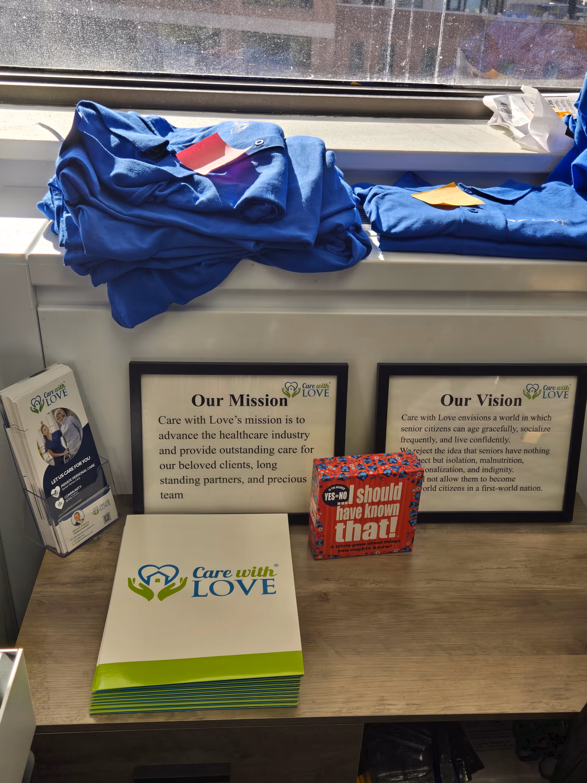 Folded blue uniforms, framed mission posters, and brochures on a desk by a window.