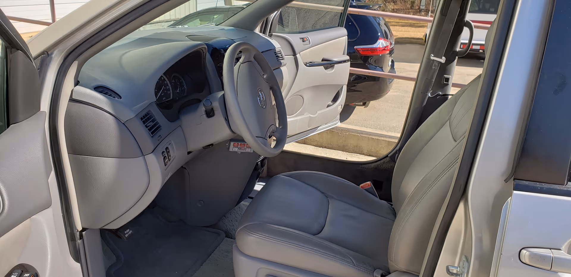 Front driver's area of a vehicle with steering wheel and dashboard visible.