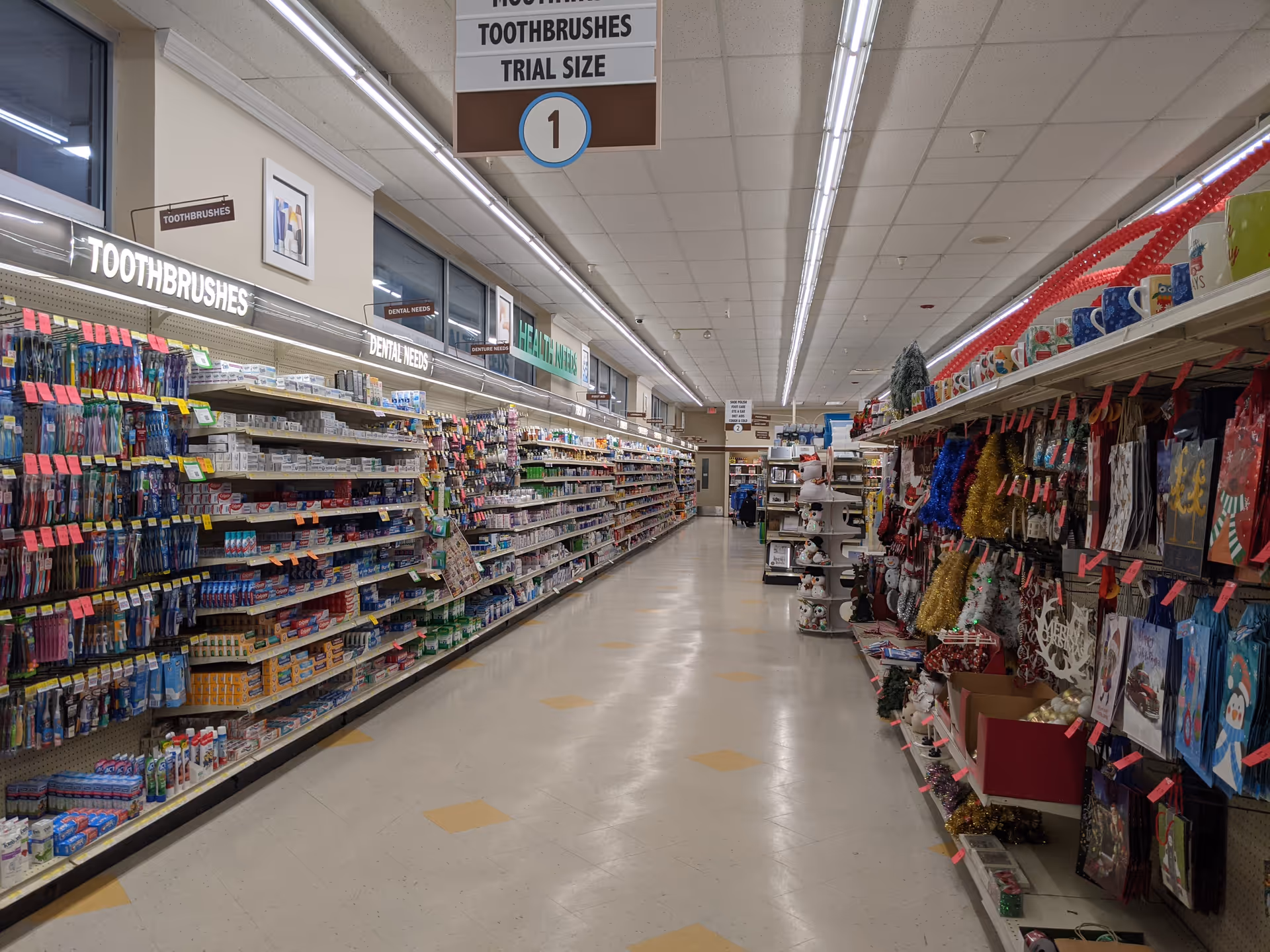 Wide store aisle inside Discount Drug Mart, lined with toothbrushes and dental products.