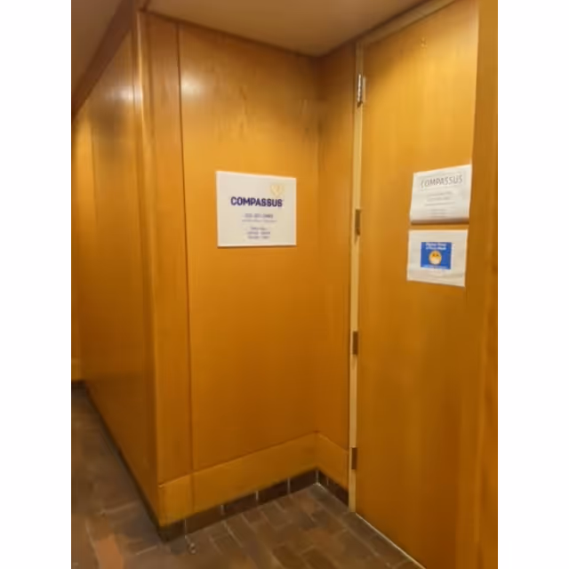Wood-paneled interior hallway with closed doors and Compassus signage.