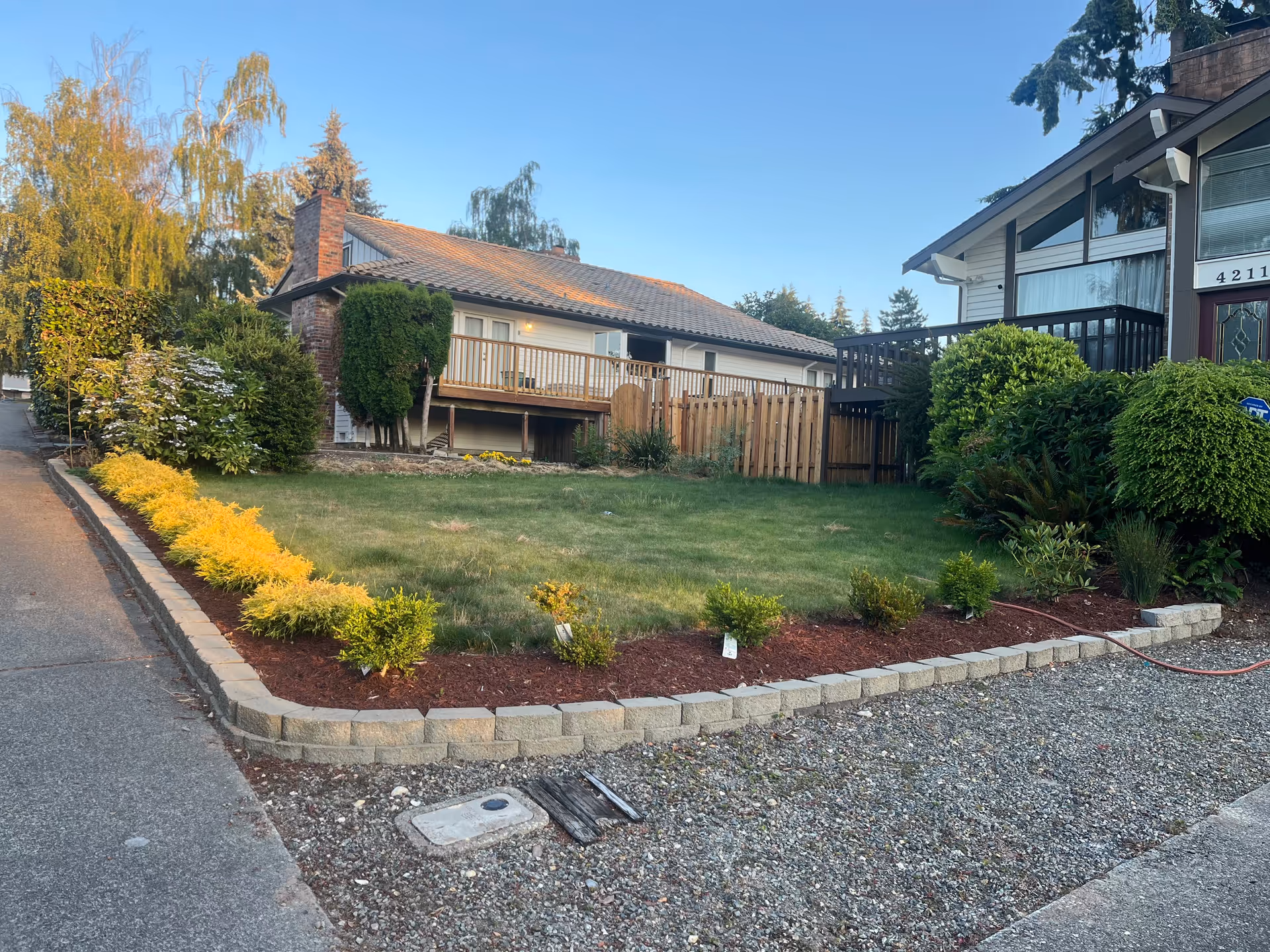 Outdoor view of a landscaped front yard with a stone border and neighboring homes