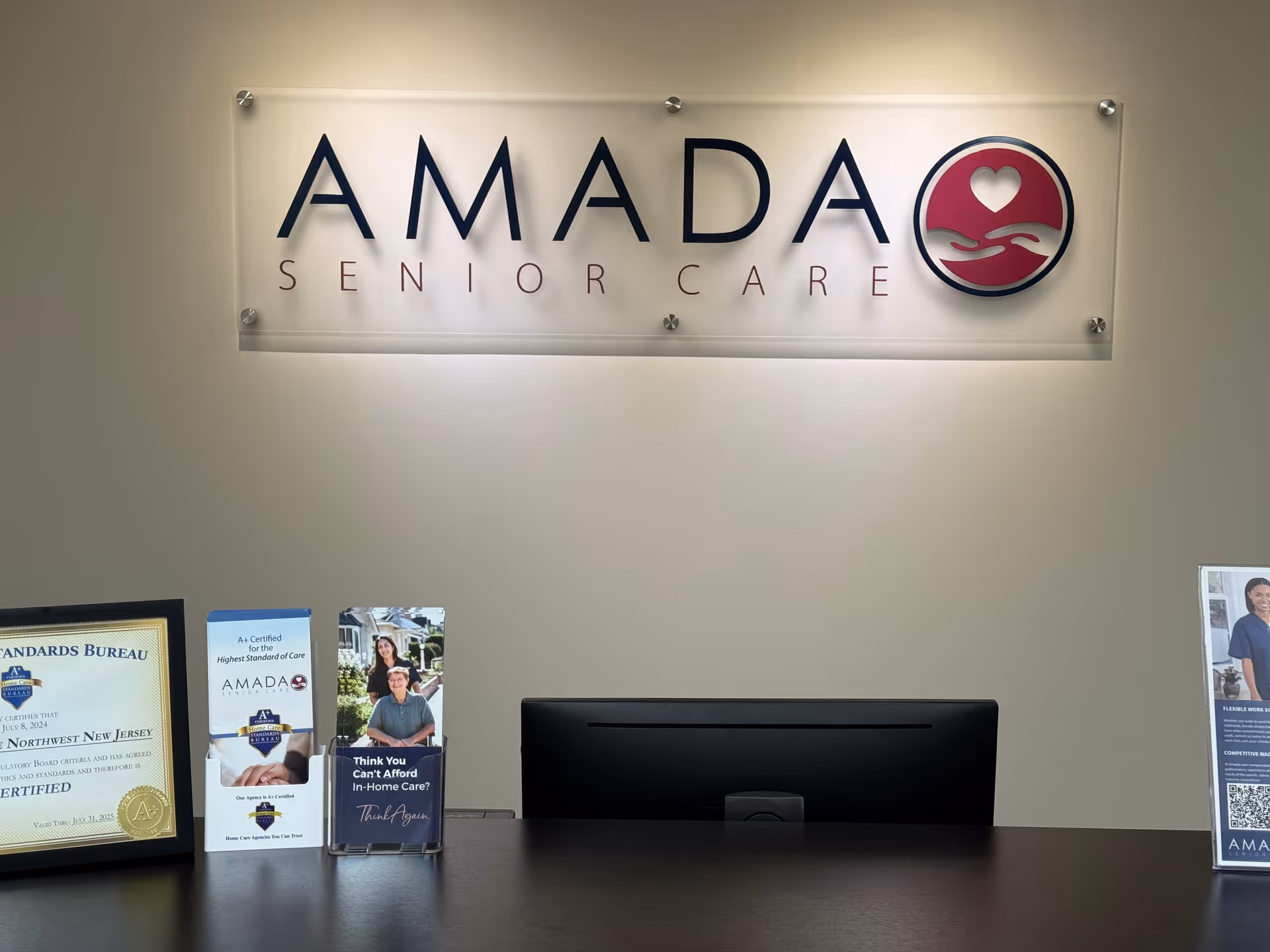 Reception desk with Amada Senior Care sign and brochures in a lobby.