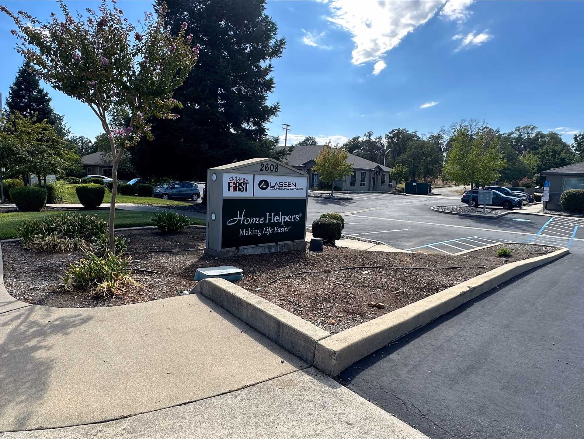 Exterior view of Home Helpers Home Care facility with sign and parking area.