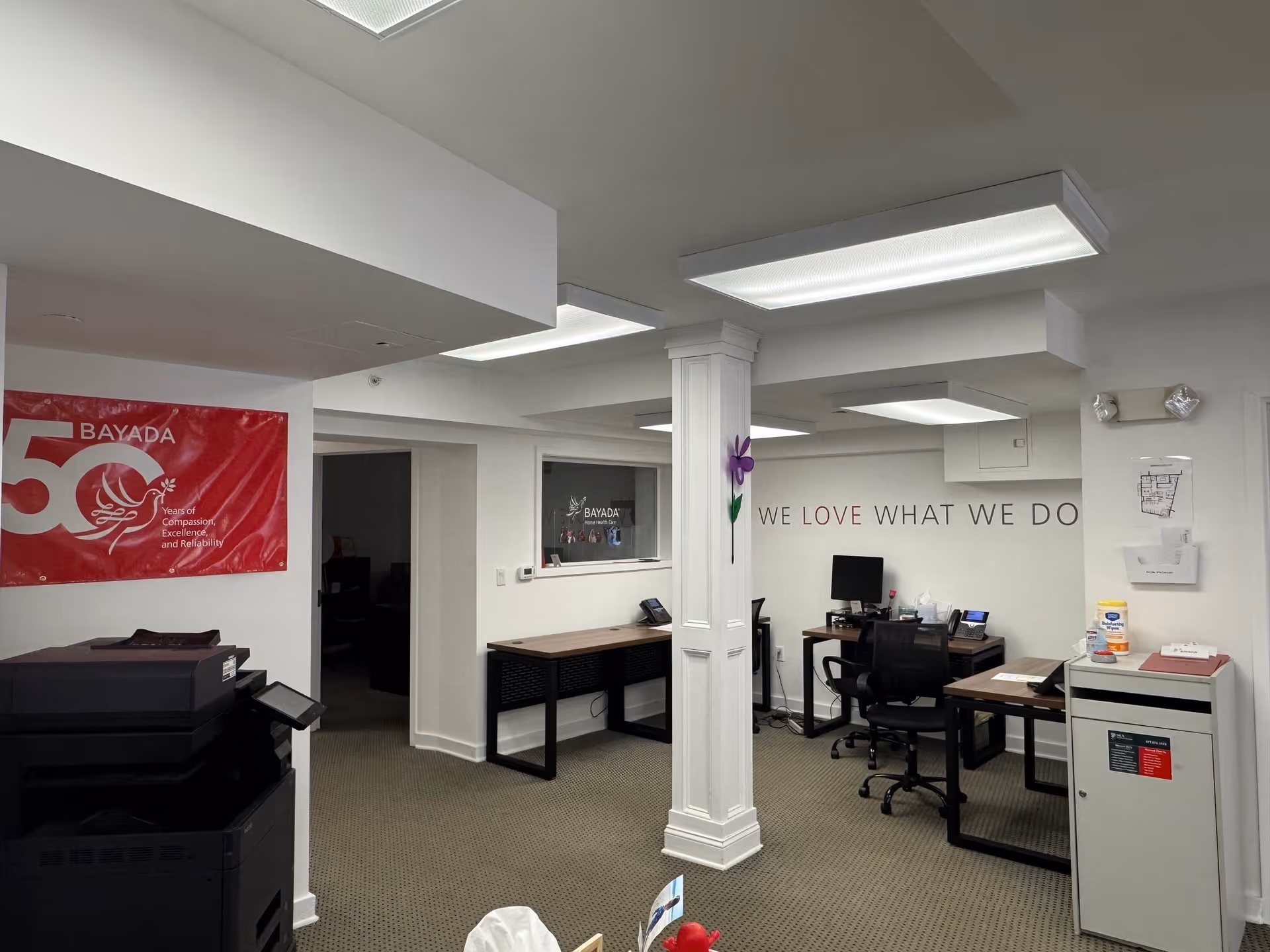 Interior office area with desks, a central pillar, and a BAYADA banner on the wall.