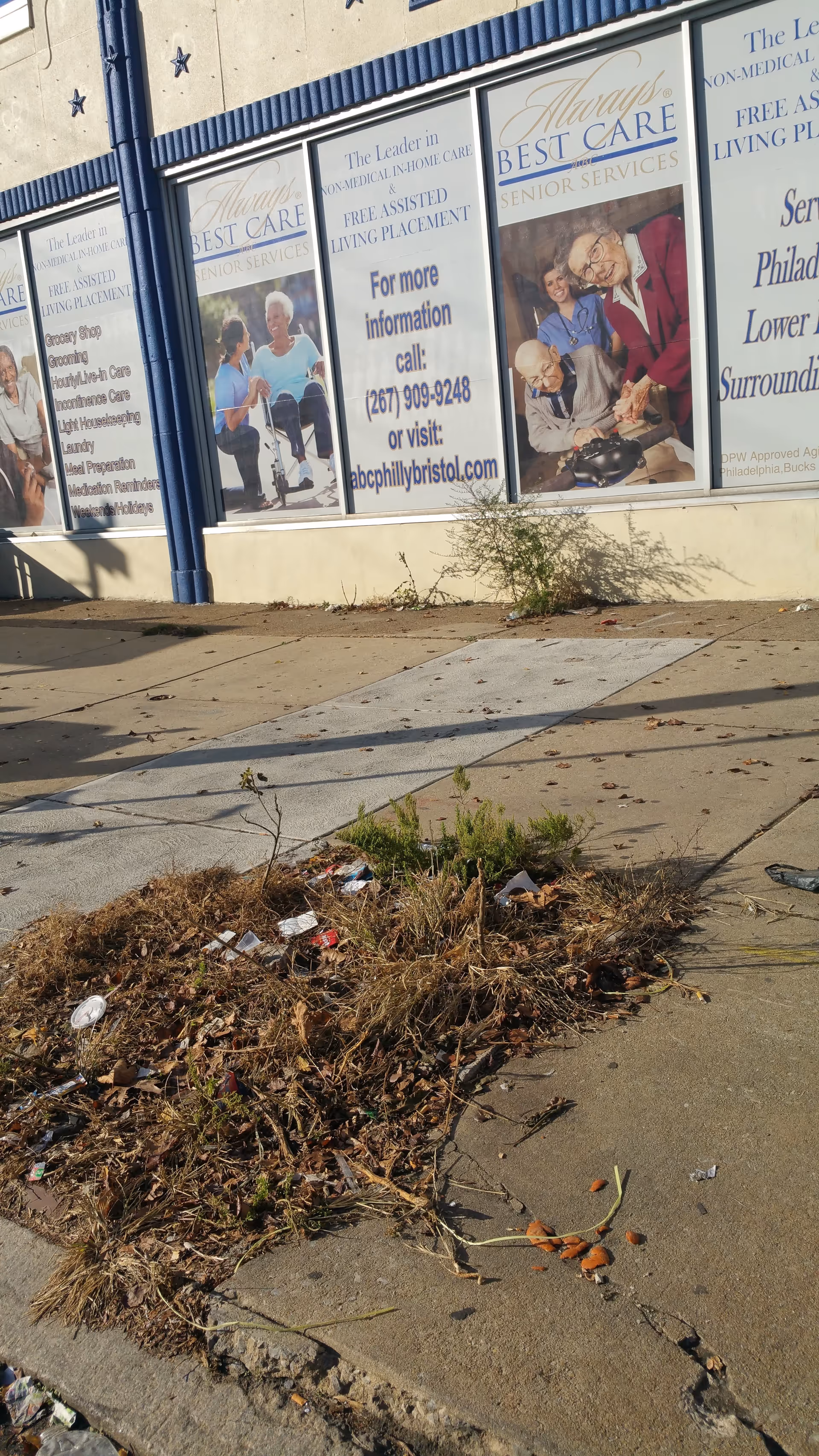 Storefront windows advertise Always Best Care Senior Services, with weeds and litter outside.