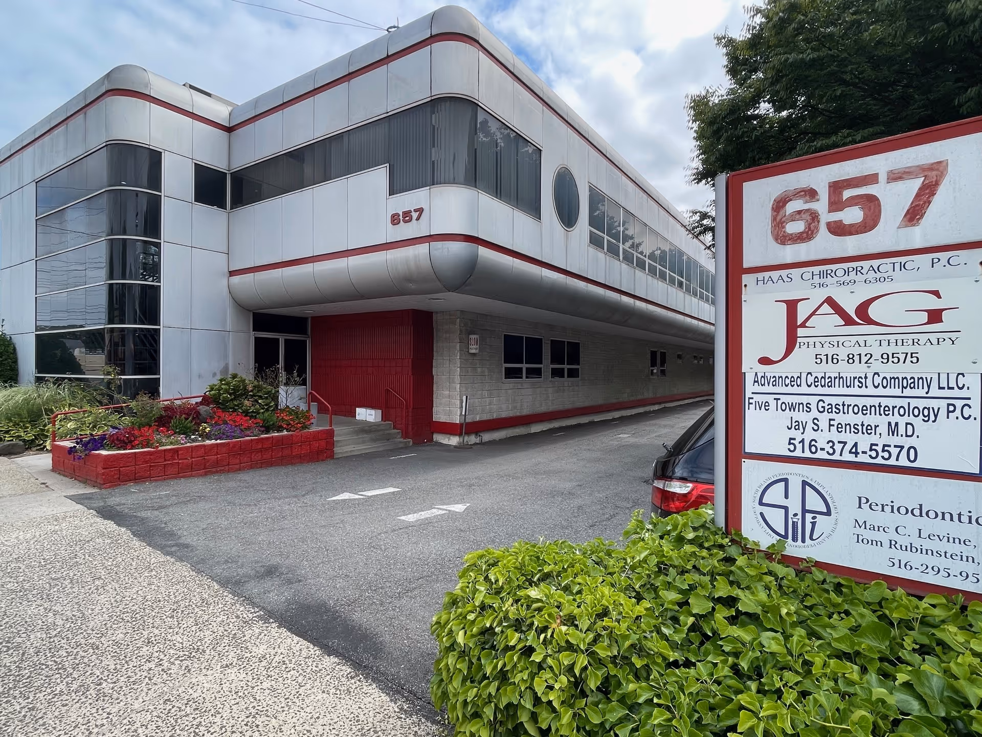 Exterior view of a modern white building with red trim and a JAG Physical Therapy sign.