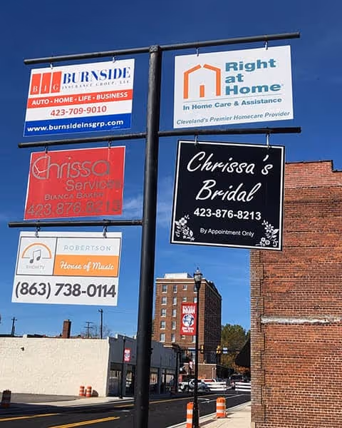 A tall signpost with multiple business signs, including Right at Home, outside a brick building.