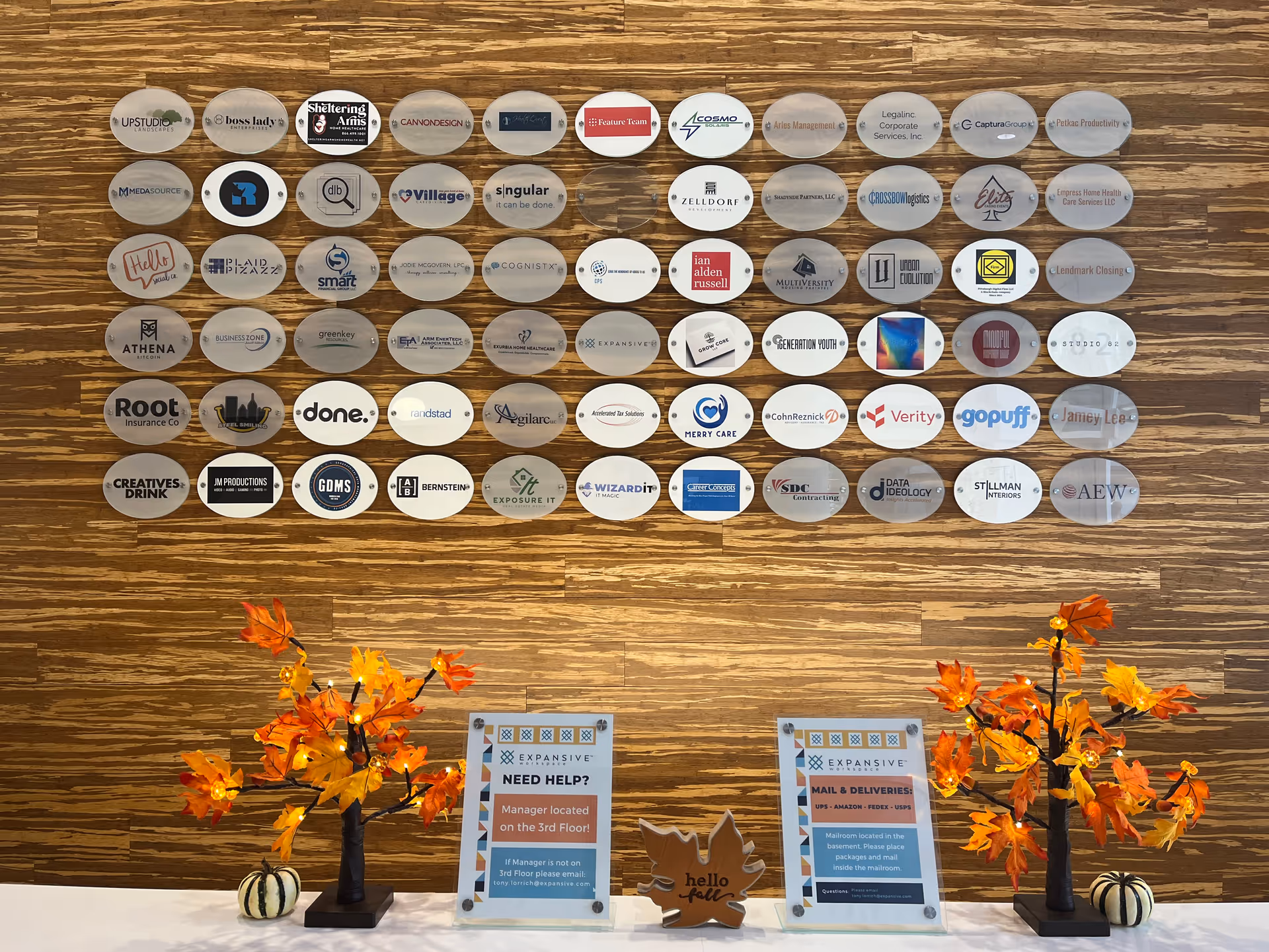 Lobby wall adorned with circular logos, autumn arrangements, and 'Need Help' signs.