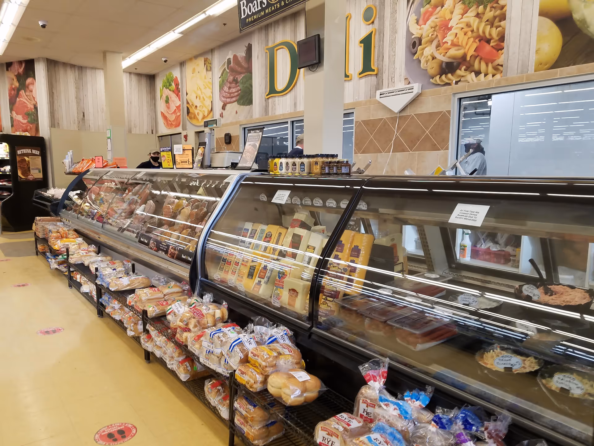 Inside a Discount Drug Mart, a long deli display case with meat and bread.
