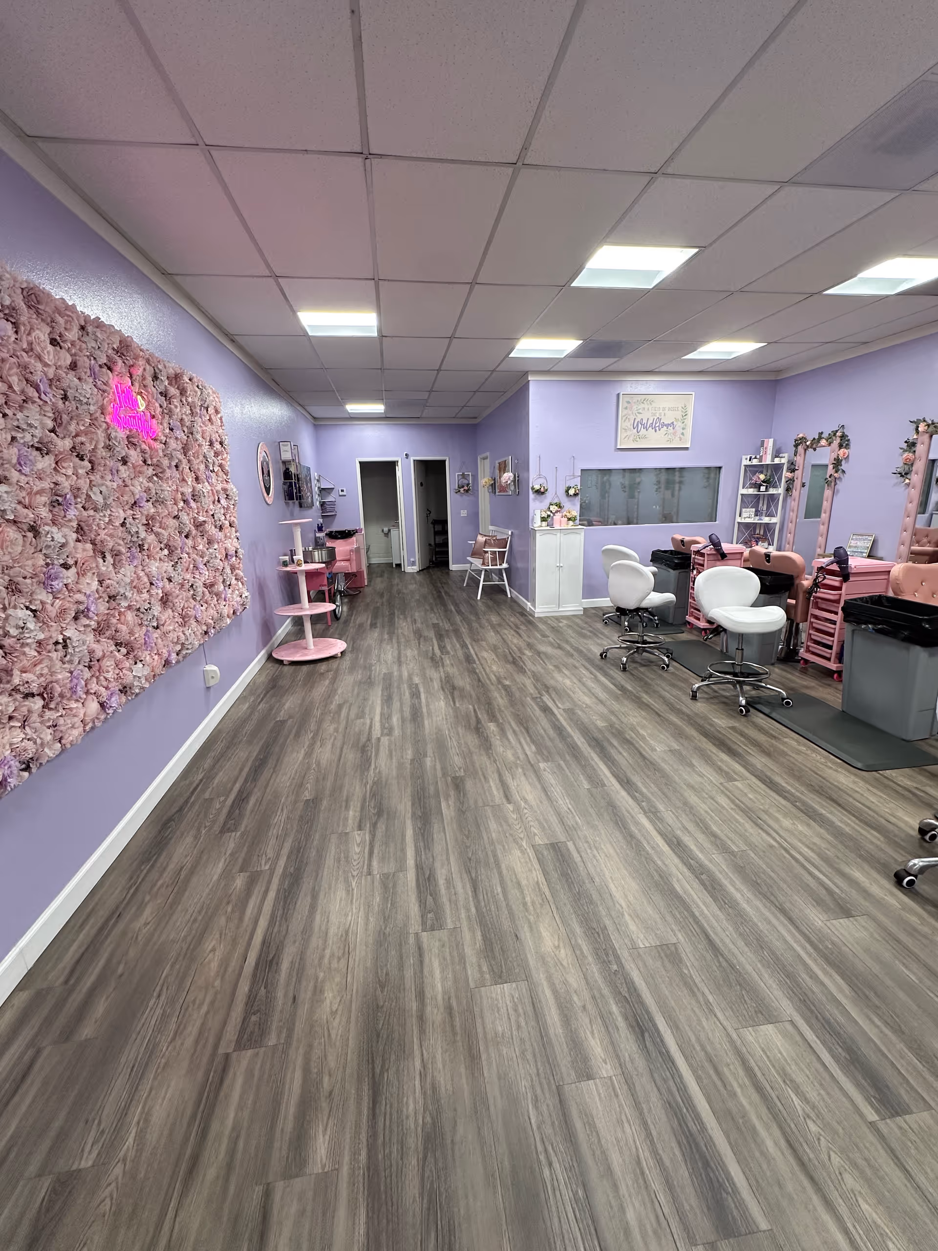Lavender salon interior with pink floral accent wall, styling stations, mirrors, and purple decor.