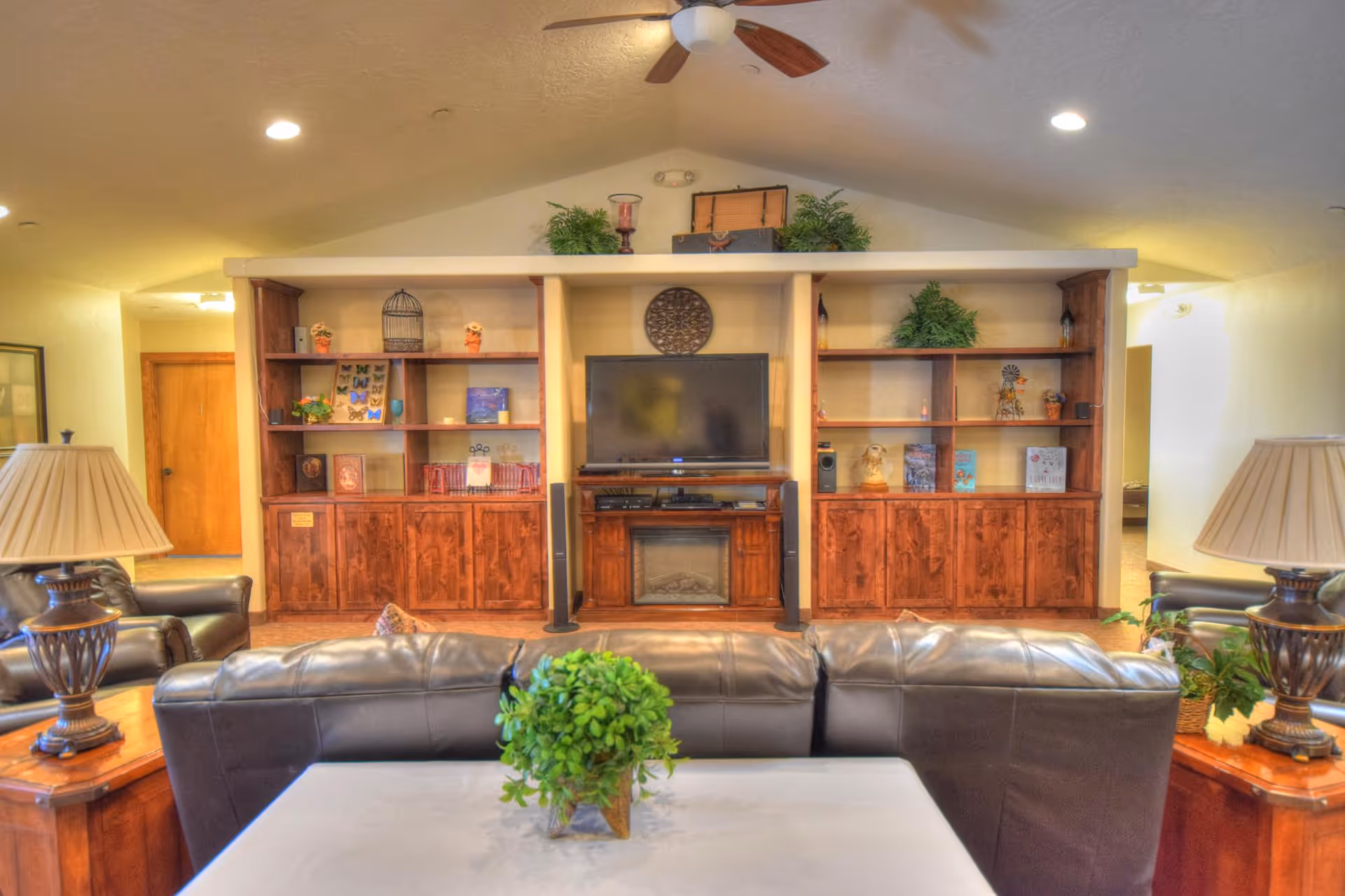 Cozy living room with leather sofas, a central TV, and open shelving.