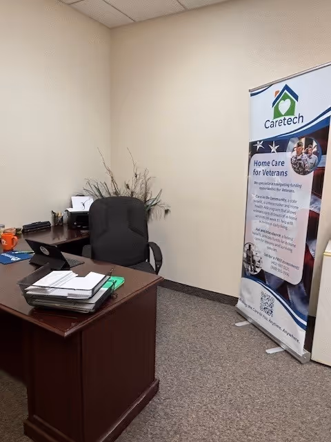 An office with a wooden desk, chair, and a Caretech banner.