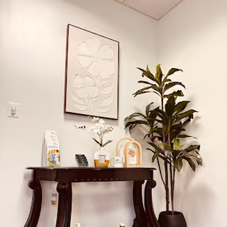 A small console table with decor and a tall plant in a white interior corner.