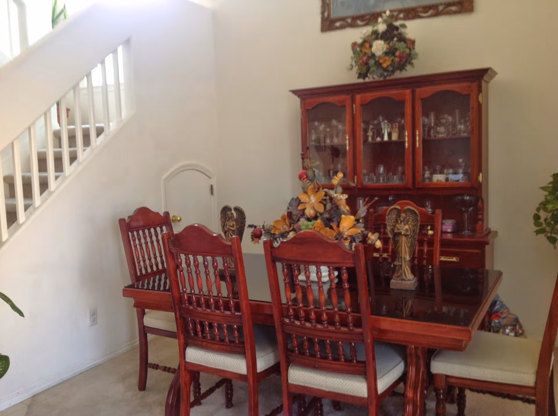 A dining room featuring a polished wooden table, chairs, and a glass-front china cabinet.