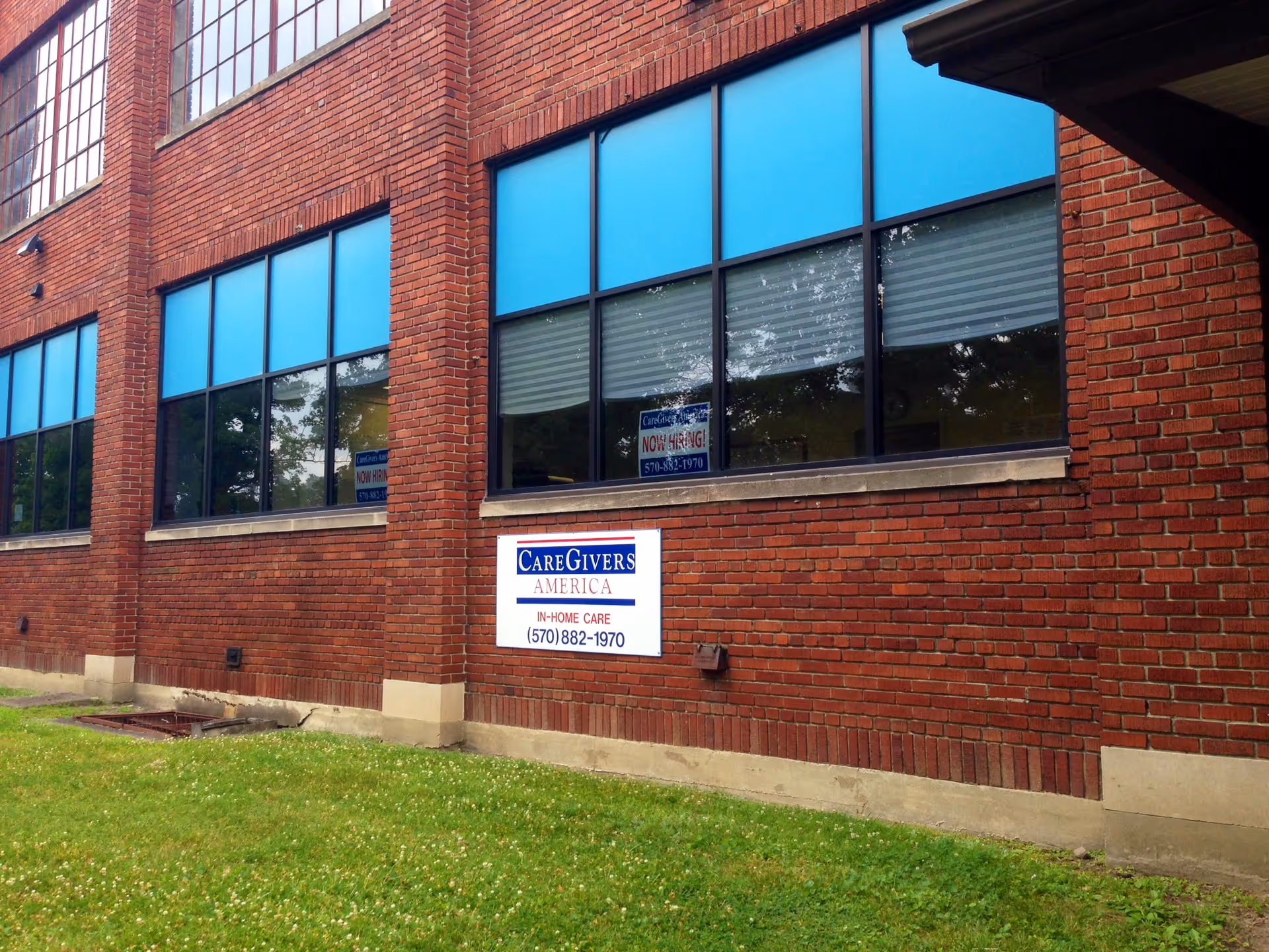 Red brick exterior of a CareGivers America building with blue-tinted windows and a sign.
