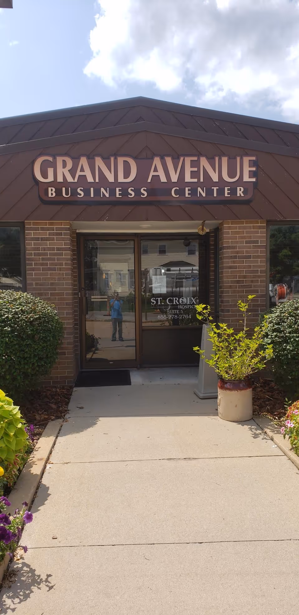Brick storefront with Grand Avenue Business Center sign and glass entrance door.
