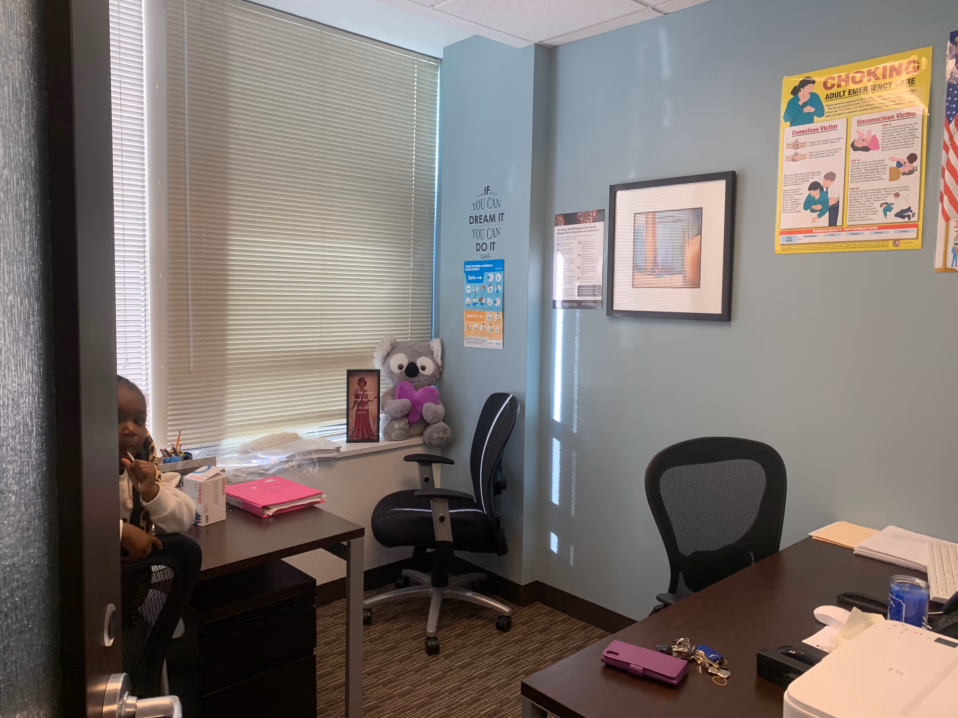 Office workspace inside a senior living facility with desk, chair, and window blinds.