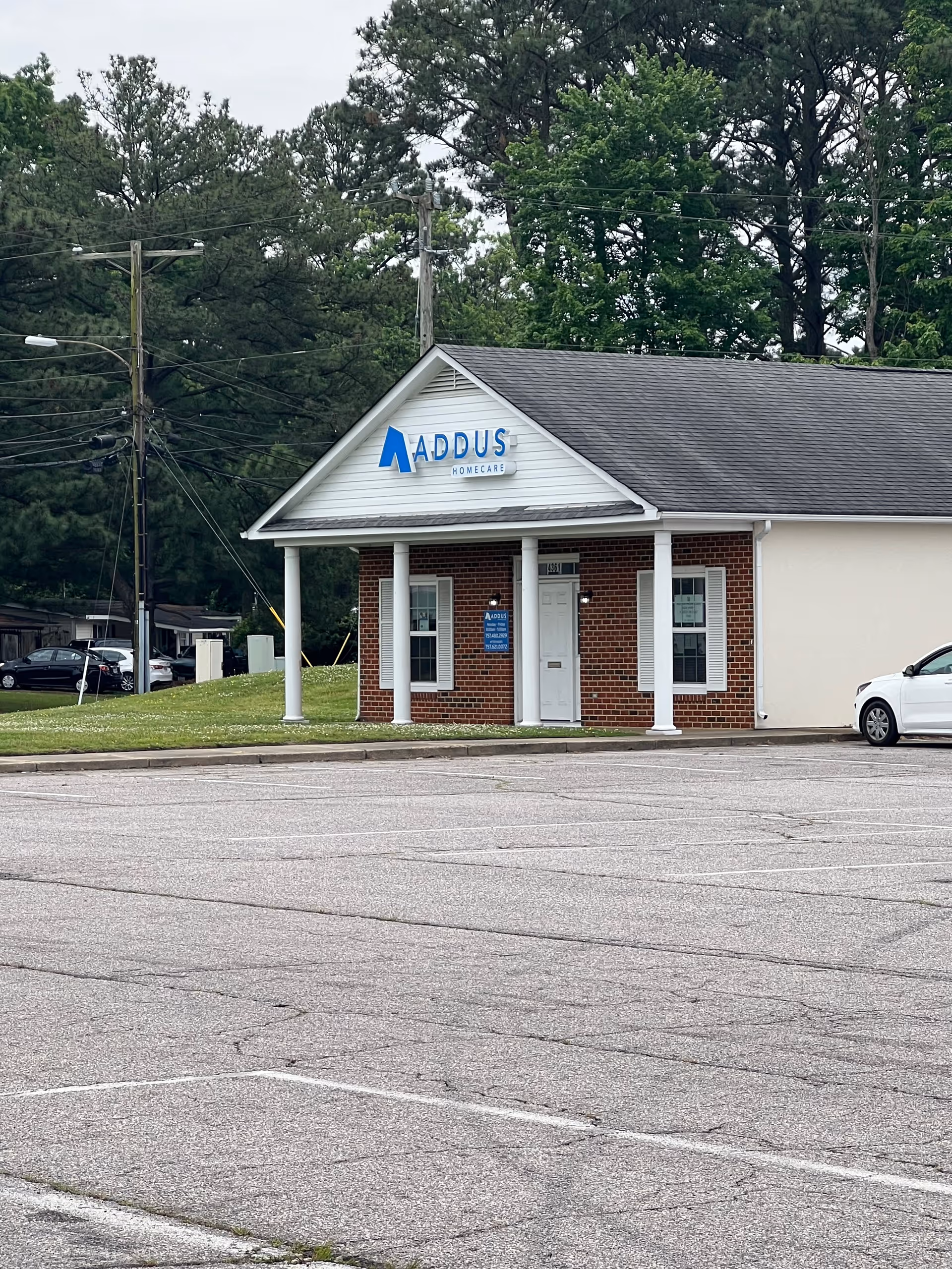 Front view of Addus HomeCare building with brick entrance and parked car.
