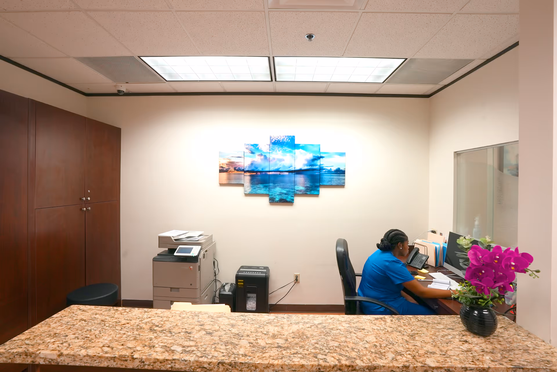 Reception area with staff at computer behind a granite counter.