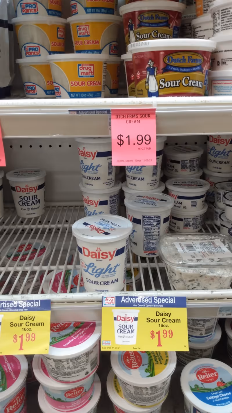 Assorted tubs of Daisy Sour Cream and other dairy products on store shelves.